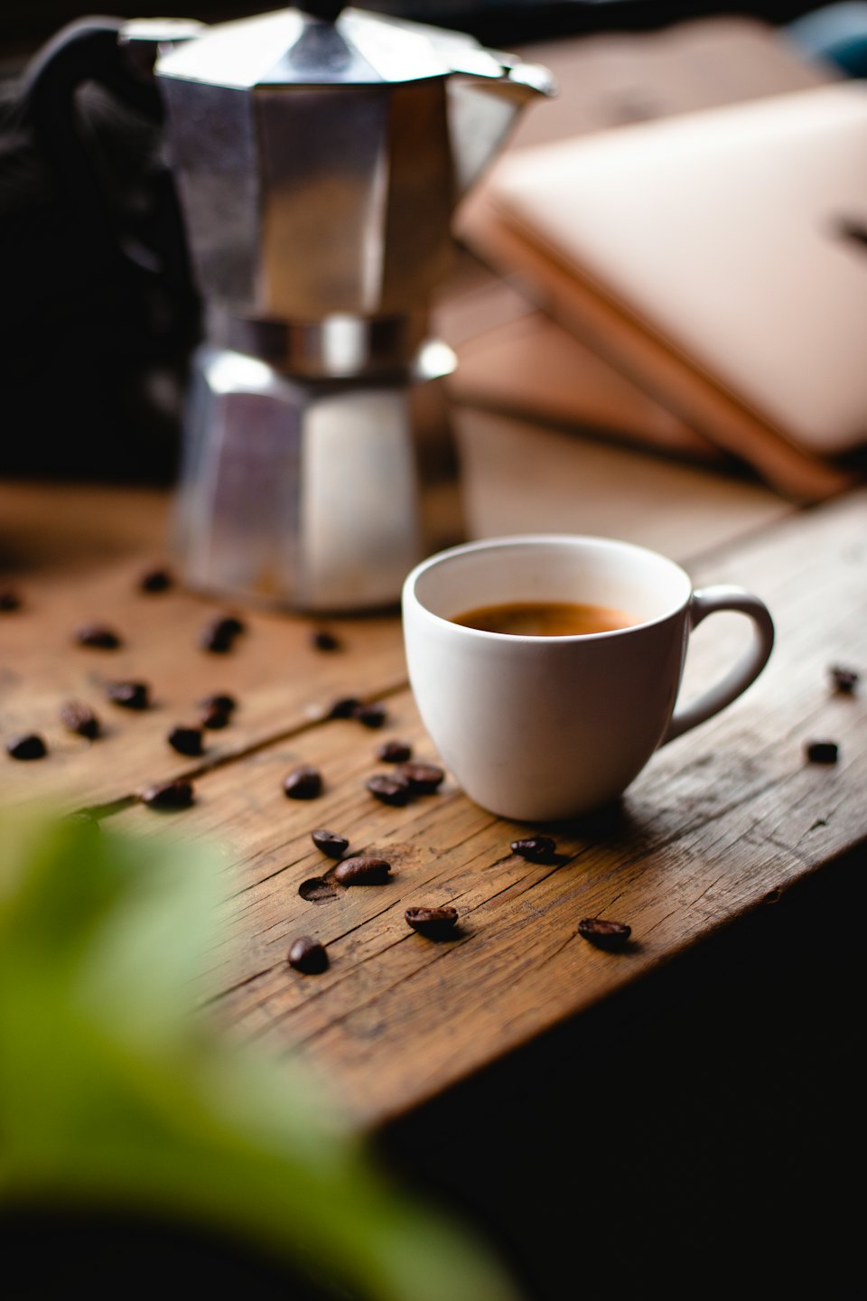 White coffee cup on a rustic wooden table with coffee beans.