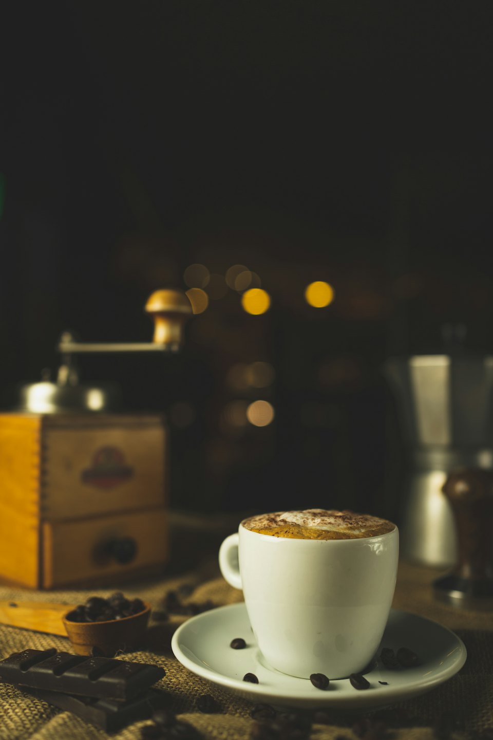 Coffee cup with cinnamon and scattered beans on burlap.