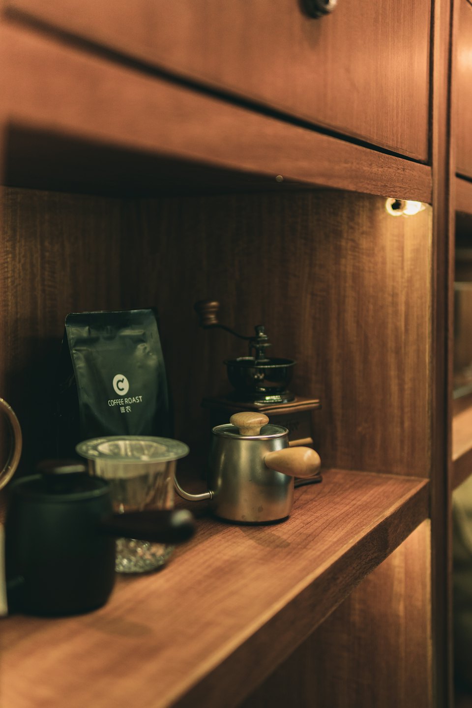Coffee brewing equipment and coffee beans arranged on a wooden shelf.